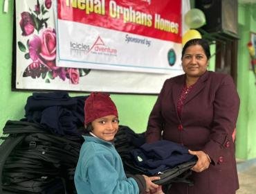 Indira handing over the school bags and winter dress